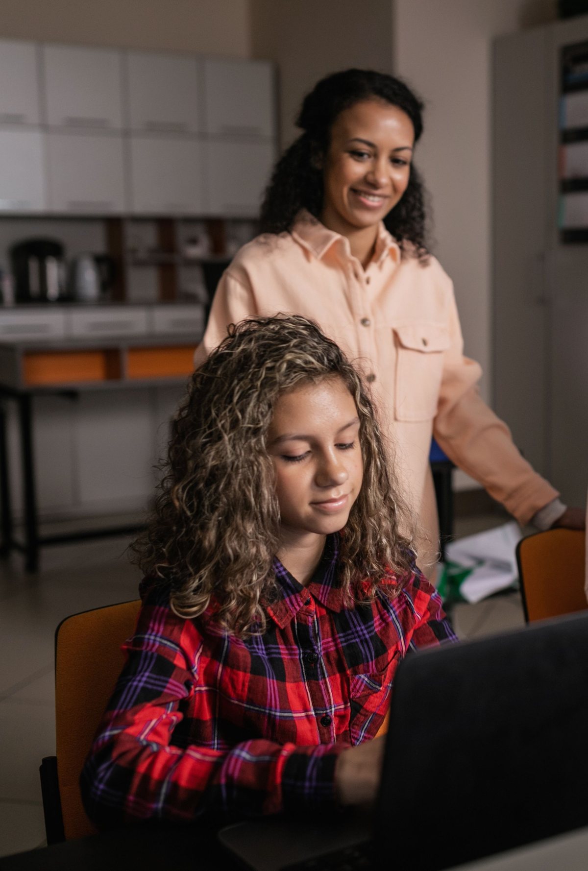 High school counselor supporting a student as she works on a computer.
